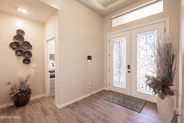 foyer entrance featuring french doors, baseboards, and wood finished floors