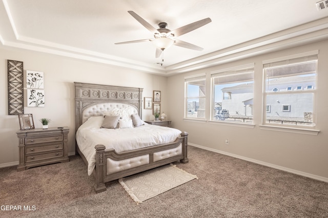 bedroom with carpet, a raised ceiling, and baseboards