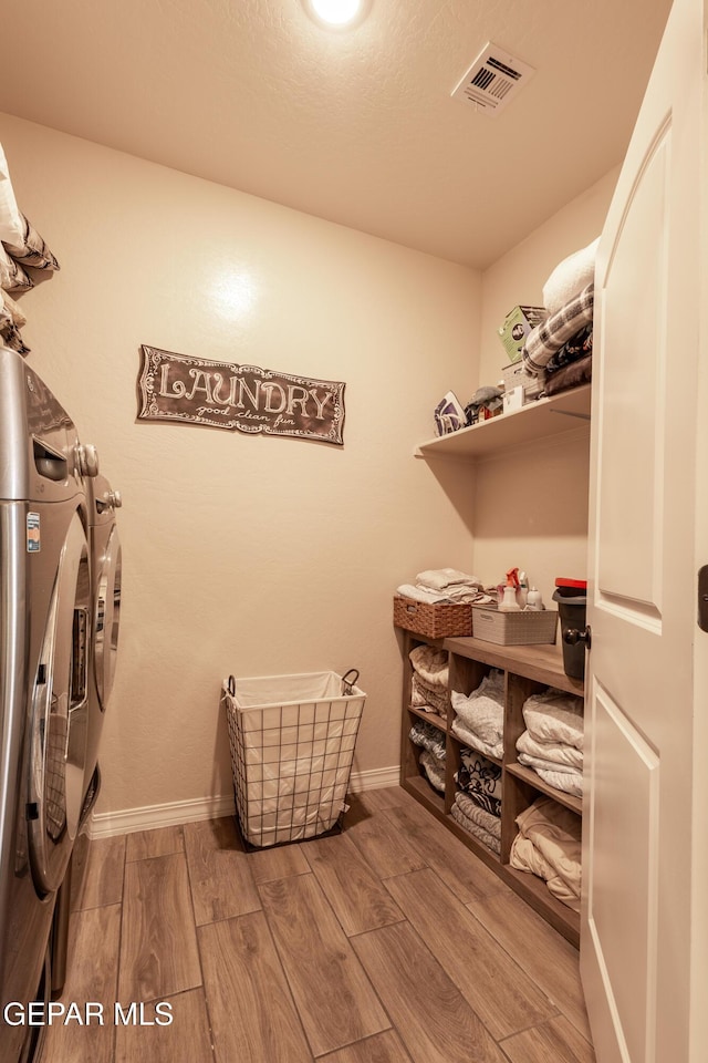 spacious closet featuring washer and dryer, visible vents, and wood finish floors