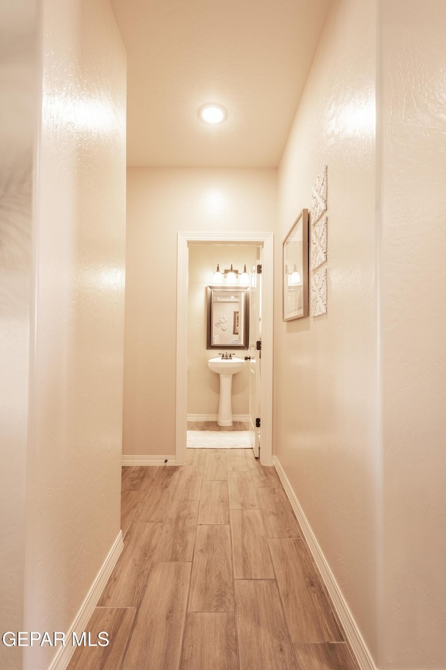 corridor with a sink, baseboards, and wood finished floors