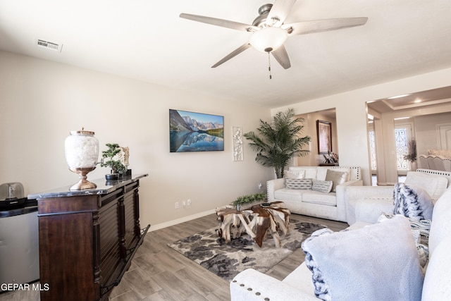 living area featuring ceiling fan, wood finished floors, visible vents, and baseboards