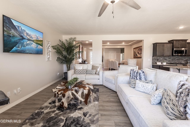 living area with a ceiling fan, baseboards, and wood finished floors