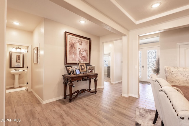 hall featuring baseboards, recessed lighting, a sink, and light wood-style floors