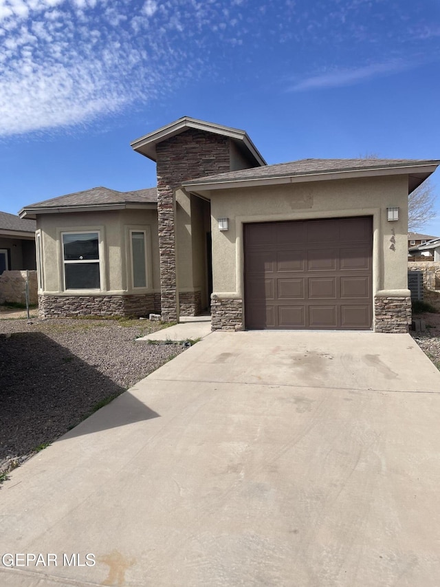 prairie-style home featuring a garage, stone siding, concrete driveway, and stucco siding