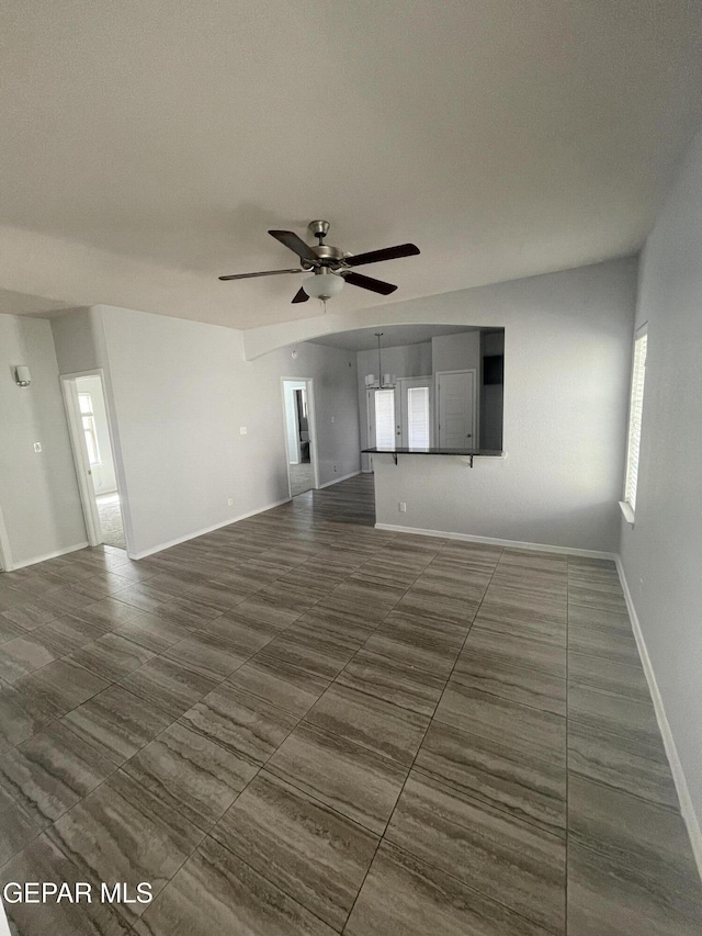 unfurnished living room with baseboards and a ceiling fan