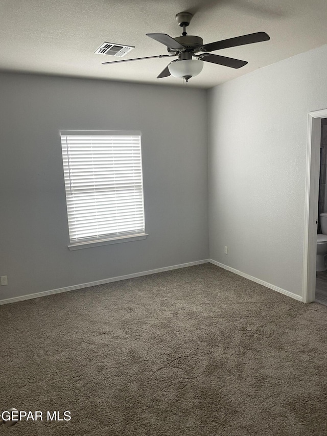 empty room featuring visible vents, carpet flooring, ceiling fan, a textured ceiling, and baseboards