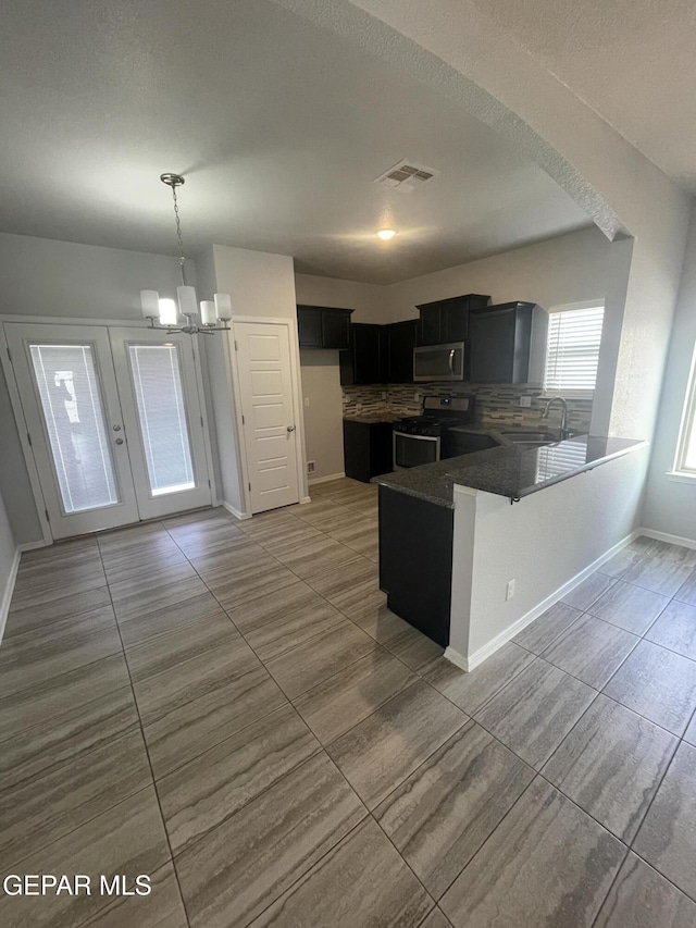 kitchen featuring stainless steel appliances, a peninsula, a sink, visible vents, and decorative backsplash