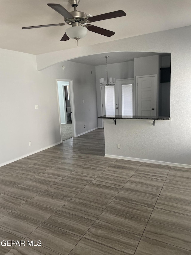 empty room with baseboards and ceiling fan with notable chandelier