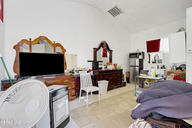 bedroom with lofted ceiling, tile patterned flooring, visible vents, and freestanding refrigerator