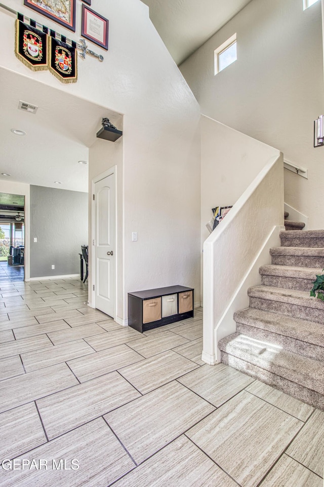 stairway featuring plenty of natural light, visible vents, baseboards, and wood finish floors