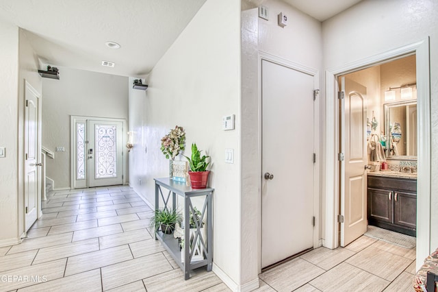 foyer with baseboards, visible vents, and wood finish floors