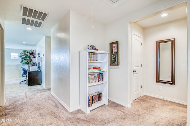 corridor with baseboards, visible vents, and light colored carpet