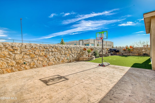 view of patio / terrace featuring a fenced backyard and basketball hoop