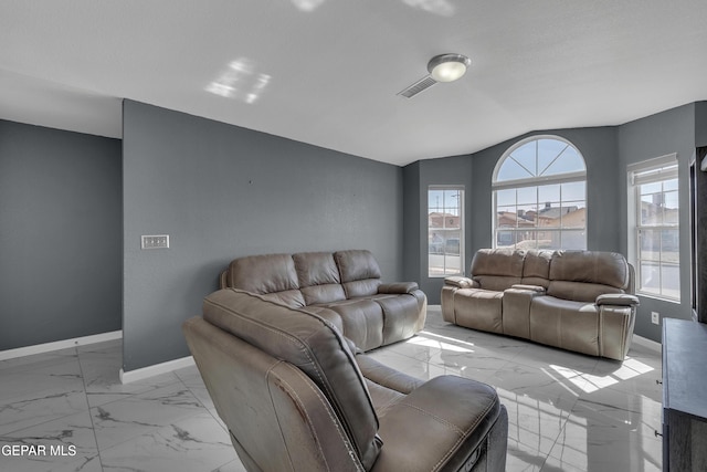 living area featuring vaulted ceiling, marble finish floor, visible vents, and baseboards