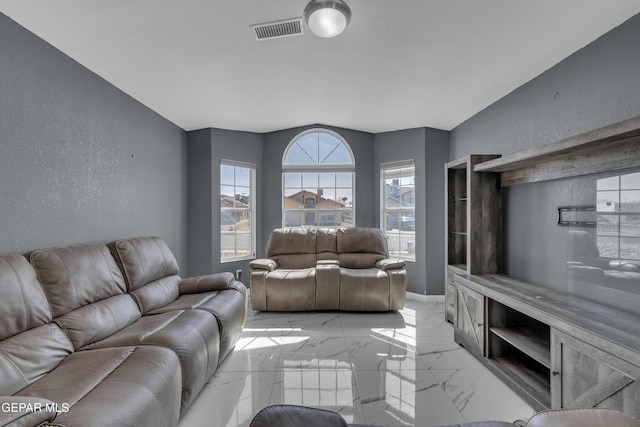 living room featuring marble finish floor, visible vents, a textured wall, and baseboards