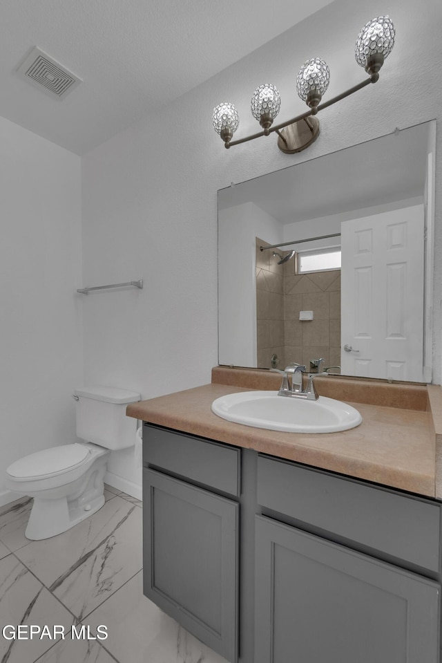 full bath featuring toilet, vanity, visible vents, marble finish floor, and walk in shower