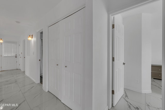 corridor featuring marble finish floor and baseboards