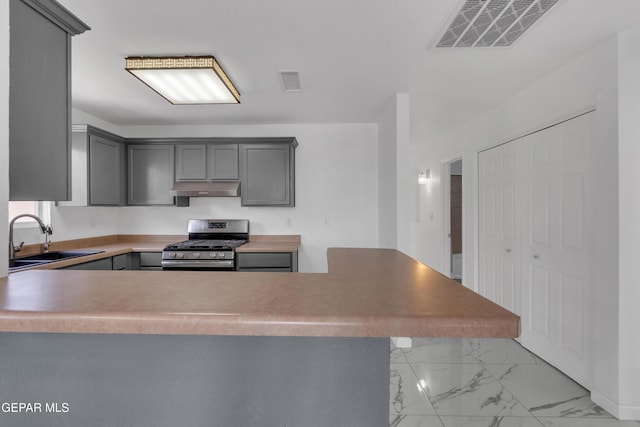 kitchen with under cabinet range hood, a sink, visible vents, gray cabinets, and stainless steel gas stove