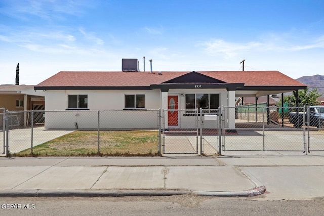 ranch-style home featuring a fenced front yard, a gate, central air condition unit, and stucco siding