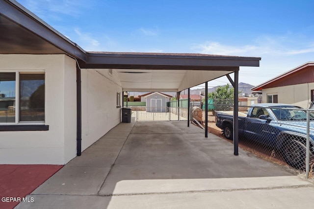 view of car parking featuring a carport, a gate, fence, and a storage shed