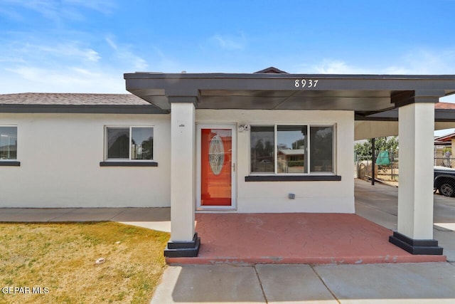 doorway to property featuring roof with shingles and stucco siding