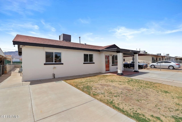 single story home featuring a front lawn, central air condition unit, fence, and stucco siding