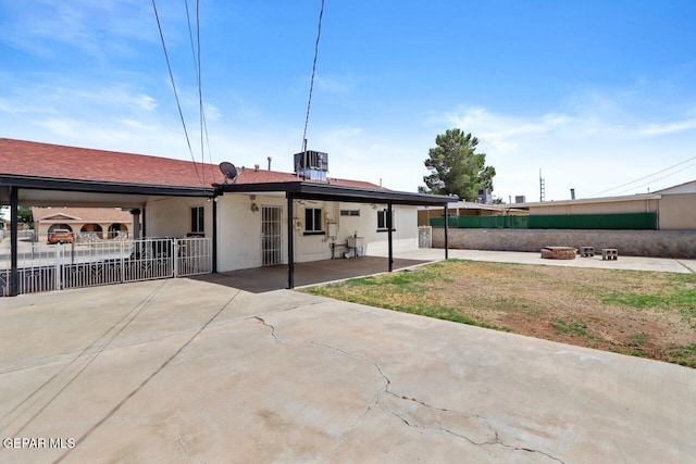 rear view of property featuring central AC unit, a fire pit, a patio, fence, and stucco siding