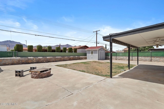 view of patio / terrace featuring a storage shed, an outdoor fire pit, an outbuilding, and a fenced backyard