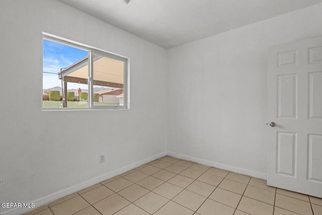 empty room featuring baseboards and light tile patterned flooring