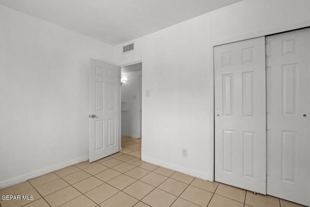 unfurnished bedroom featuring light tile patterned floors, baseboards, visible vents, and a closet