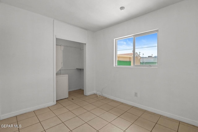 unfurnished bedroom with light tile patterned floors, a closet, and baseboards