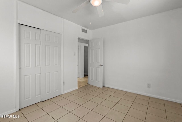 unfurnished bedroom featuring light tile patterned floors, a closet, visible vents, a ceiling fan, and baseboards