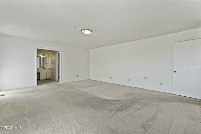 empty room with a textured ceiling and light colored carpet