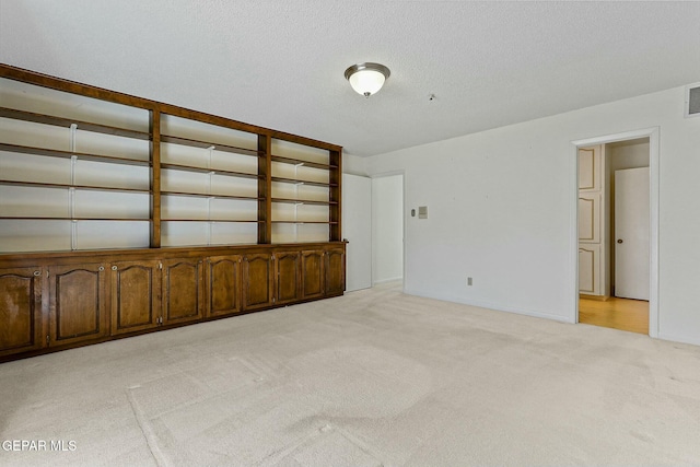 unfurnished room featuring light carpet, visible vents, and a textured ceiling