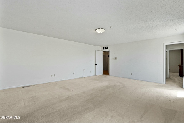 spare room featuring baseboards, visible vents, a textured ceiling, and light colored carpet