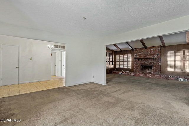 unfurnished living room with visible vents, a textured ceiling, carpet floors, a fireplace, and a chandelier