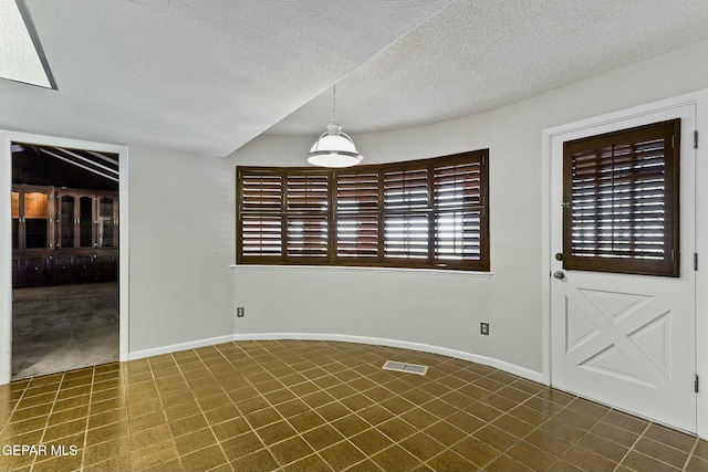 unfurnished dining area featuring visible vents, a textured ceiling, and baseboards