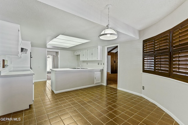 kitchen with baseboards, light countertops, a textured ceiling, and white cabinets