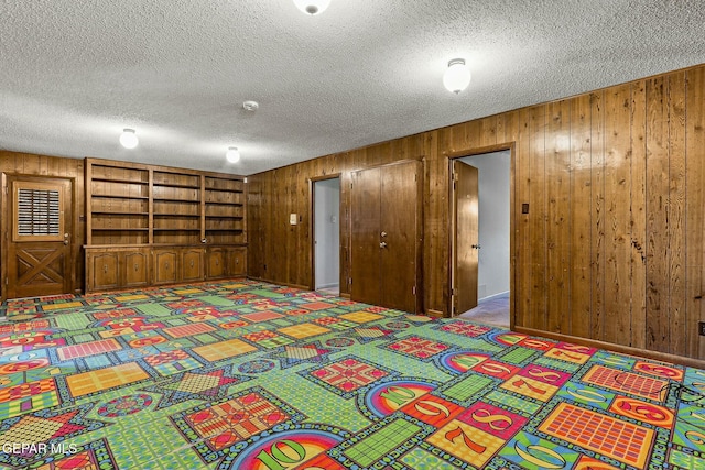 interior space featuring wood walls, a closet, a textured ceiling, and carpet flooring