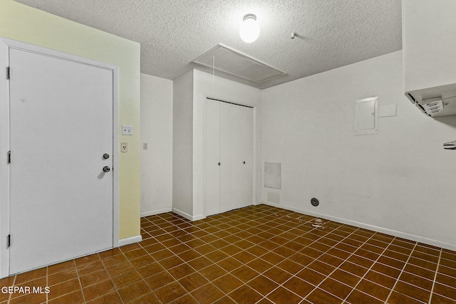 spare room with attic access, baseboards, and a textured ceiling