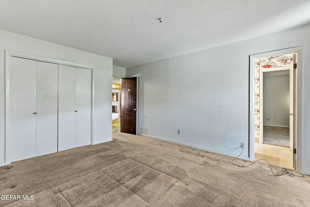 unfurnished bedroom featuring carpet, a closet, a textured ceiling, and baseboards