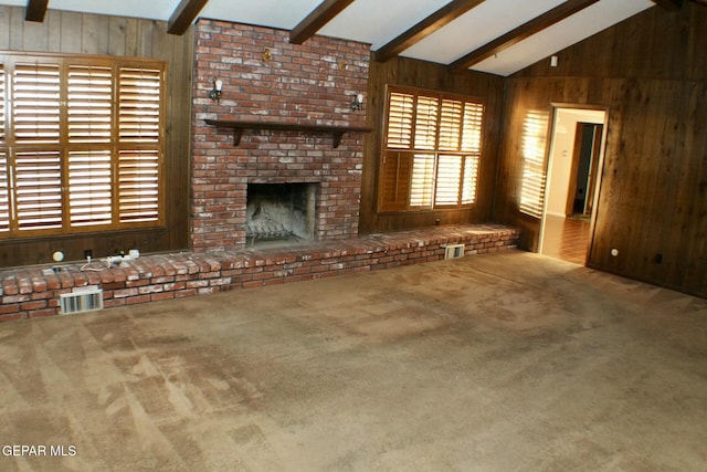 unfurnished living room featuring a brick fireplace, carpet, wooden walls, and visible vents