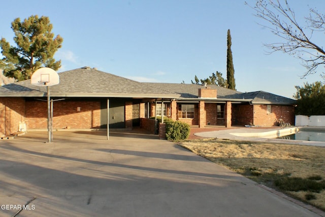 view of front of home with brick siding, a chimney, a patio area, and an outdoor pool