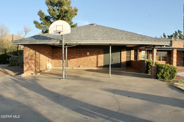 exterior space featuring brick siding and roof with shingles