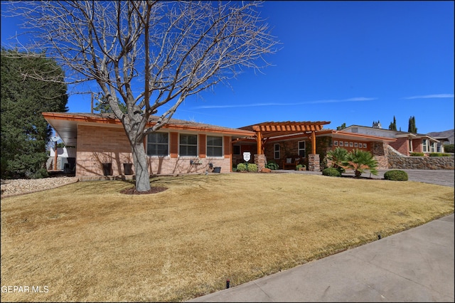 view of front facade with brick siding, a pergola, and a front yard