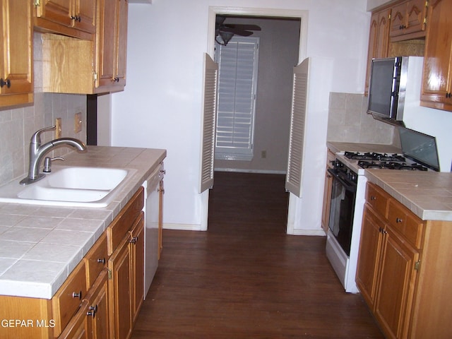 kitchen with tile countertops, gas stove, a sink, dark wood-type flooring, and brown cabinets