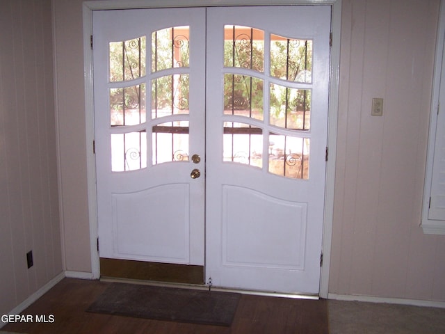 entryway with french doors, baseboards, wood finished floors, and wood walls