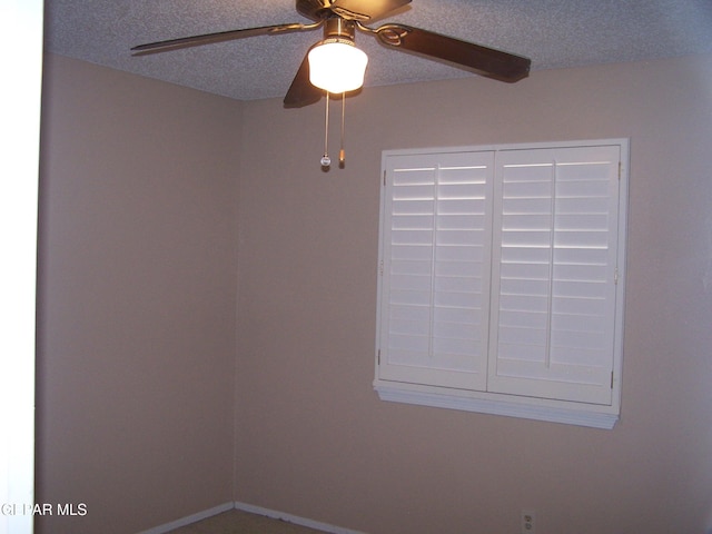 empty room with a textured ceiling and a ceiling fan