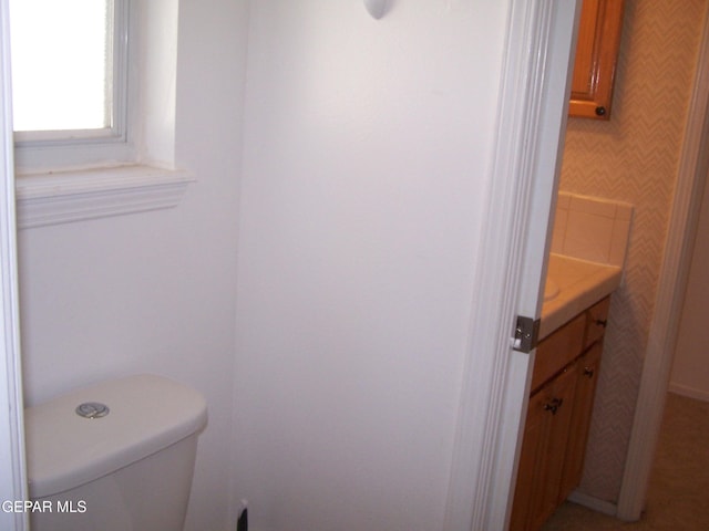 bathroom with vanity, toilet, and wallpapered walls