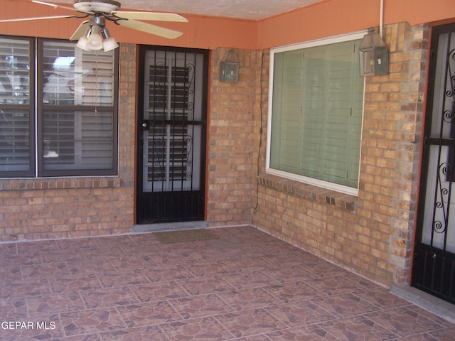 property entrance featuring brick siding and ceiling fan